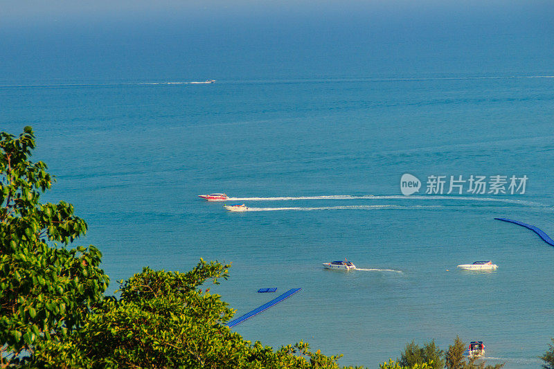 美丽的蓝色海景和水上旅游活动，如在Koh Sire海滩上划船，游艇巡航和水上摩托艇。这张照片拍摄于泰国普吉市Wat Sire temple山的山顶。
